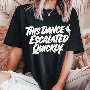 Puede incluir: Camiseta negra con el texto blanco "THIS DANCE ESCALATED QUICKLY" y una silueta de bailarina. Una prenda informal para uso diario.