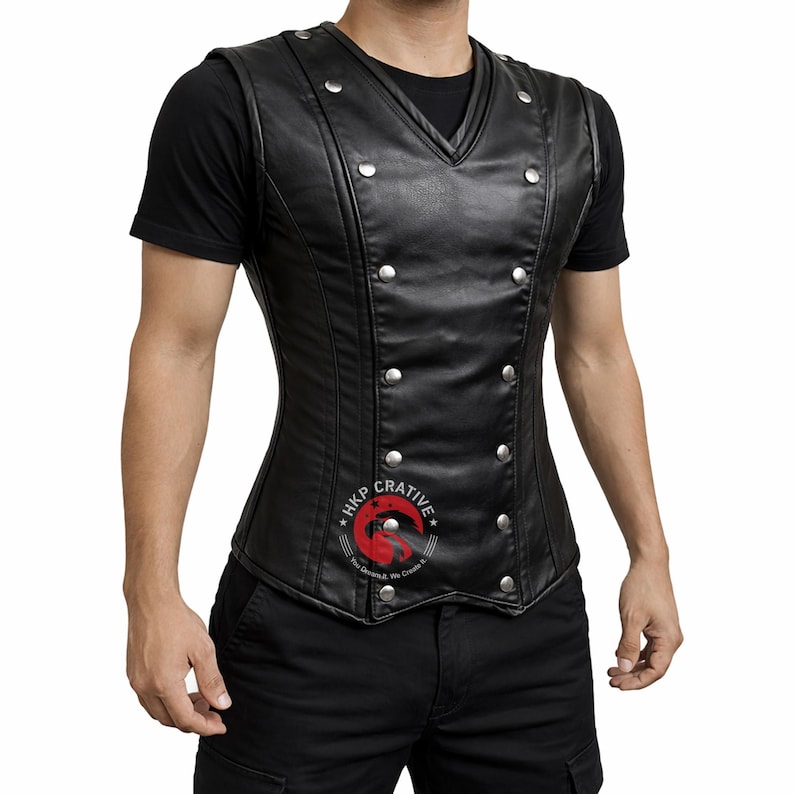 May include: A black leather vest with a V-neck and silver-colored button details. The vest has a double-breasted design and a fitted silhouette. The vest is sleeveless and appears to be worn over a black t-shirt.