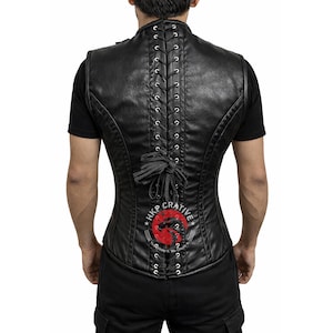 May include: Black leather vest with a lace-up back and a high collar. The vest features a red and white graphic on the lower back with the text "HKP CRATIVE". The vest is sleeveless and has a fitted silhouette.