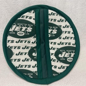 May include: Green and white round pot holder with the New York Jets logo and the words "Jets" repeated around the edge.