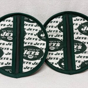 May include: Two green and white pot holders with the New York Jets logo and the words "Jets" repeated on them.