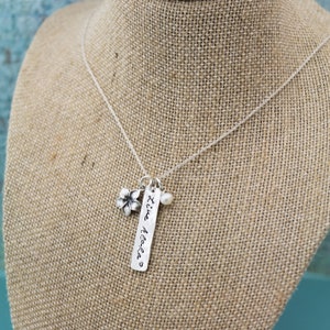 May include: A silver necklace with a charm that says "'ti'e Aloha" and a small flower charm and a pearl charm.