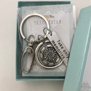 May include: Silver keychain with a compass charm and a tag that reads "Take only memories..." The keychain is in a light blue gift box with a white lace design.