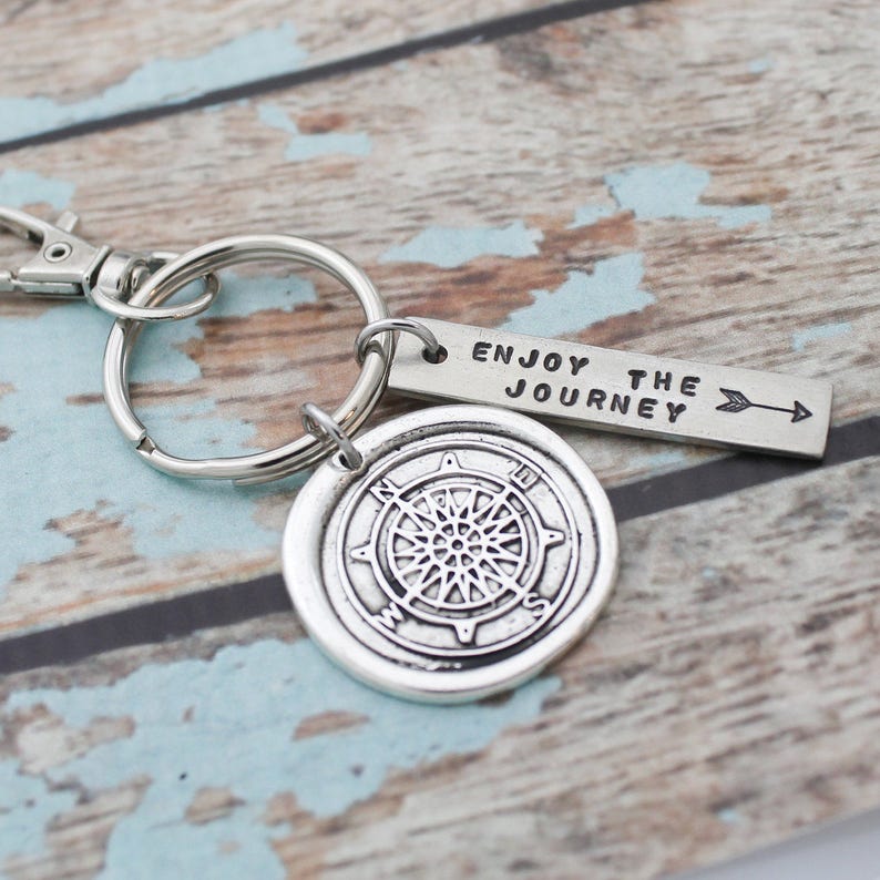 May include: Silver compass keychain with a silver tag that reads "Enjoy the Journey" with an arrow pointing to the right.