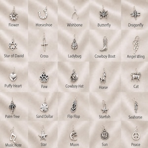 May include: A collection of twenty-five silver-toned metal charms arranged in a grid, featuring various shapes including a flower, horseshoe, wishbone, butterfly, dragonfly, star of David, cross, ladybug, cowboy boot, angel wing, heart, paw, cowboy hat, horse, cat, palm tree, sand dollar, flip flop, starfish, seahorse, music note, star, moon, sun, and a peace symbol.