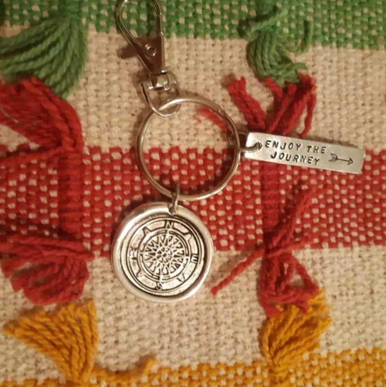 May include: Silver keychain with a compass charm and a tag that reads "Enjoy the Journey".