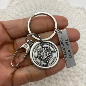 May include: Silver compass keychain with a silver tag that reads "Take only memories..."