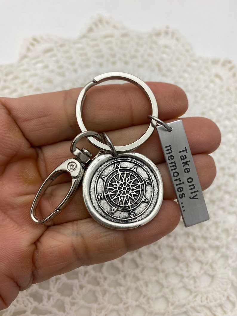 May include: Silver compass keychain with a silver tag that reads "Take only memories..."