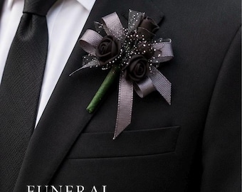 Könnte beinhalten: Eine schwarze Boutonniere mit drei dunklen Rosen, grauem Band und einem grünen Stiel, an einem schwarzen Anzugjacke befestigt. Das Bild enthält den Text "FUNERAL BOUTONNIERE" und "Handmade with Care & Respect".