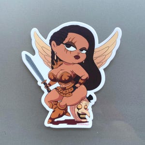 May include: A sticker featuring a cartoon warrior woman with brown skin, wearing bronze armor and holding a sword. She has long black hair, gold wings, and is standing on a grotesque mask. The sticker has a white border.