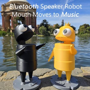 Può includere: Due robot altoparlanti Bluetooth, uno nero e uno giallo, con grandi occhi bianchi e una bocca che si muove a ritmo di musica. Il testo Bluetooth Speaker Robot Mouth Moves to Music è visualizzato sopra le figure su basi grigie.