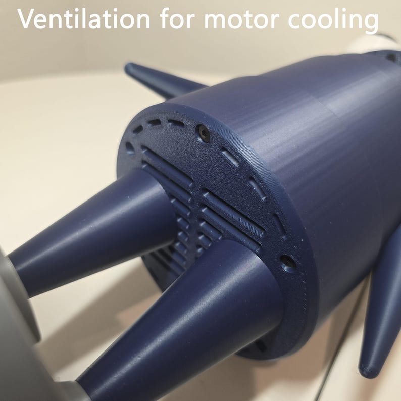 May include: A dark blue cylindrical motor housing featuring a circular end cap with integrated ventilation slots for motor cooling. The component includes several protruding conical elements and visible screw fasteners on the textured surface.