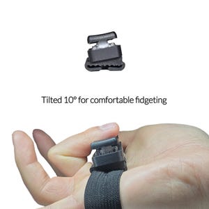 May include: A black fidget device with a white button is attached to a black elastic band. The text "Tilted 10&deg; for comfortable fidgeting" is displayed below the device. The device is designed for comfortable fidgeting.