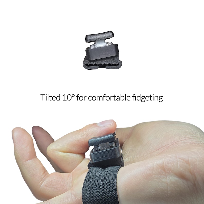 May include: A black fidget device with a white button is attached to a black elastic band. The text "Tilted 10&deg; for comfortable fidgeting" is displayed below the device. The device is designed for comfortable fidgeting.