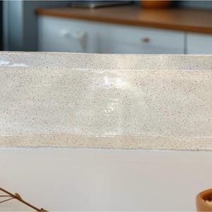 May include: A white ceramic serving tray with speckled detailing and two handles. The tray is rectangular and has a slightly raised rim.