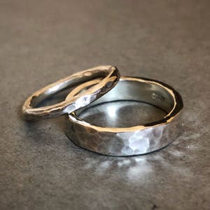 May include: Two silver hammered wedding bands. The wider band has the inscription "C1927" on the inside.
