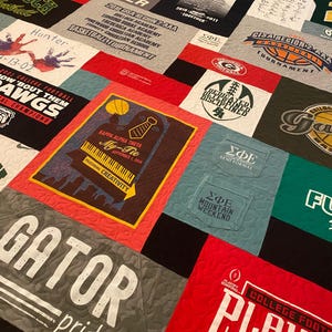 以下が含まれることがあります： さまざまなTシャツを組み合わせたパッチワークキルト。赤、緑、青、黒など、さまざまな色が使われています。キルトは正方形と長方形で構成されており、各正方形または長方形には異なるデザインが施されています。デザインには、ロゴ、テキスト、画像などがあります。キルトは、特別なイベントを記念したり、お気に入りのチームや組織をアピールしたりするのに最適な方法です。