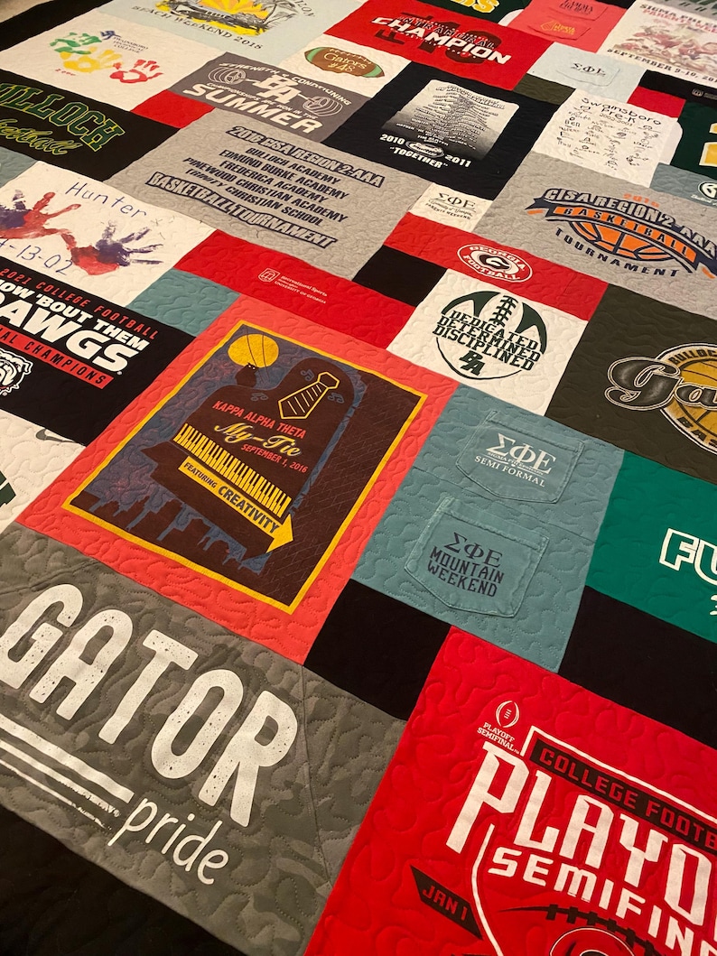 以下が含まれることがあります： さまざまなTシャツを組み合わせたパッチワークキルト。赤、緑、青、黒など、さまざまな色が使われています。キルトは正方形と長方形で構成されており、各正方形または長方形には異なるデザインが施されています。デザインには、ロゴ、テキスト、画像などがあります。キルトは、特別なイベントを記念したり、お気に入りのチームや組織をアピールしたりするのに最適な方法です。