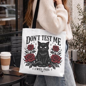 gothic tote bag with black cat and floral design on canvas bag with text "Don't Test Me, I will pass" on the bag.