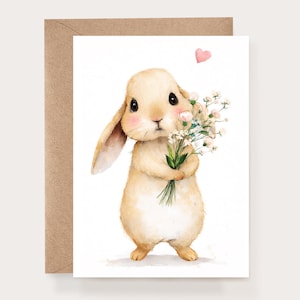 May include: A watercolor illustration of a tan bunny holding a bouquet of white flowers and a pink heart above it. The bunny has large black eyes and pink cheeks. The image is on a white background with a brown card.