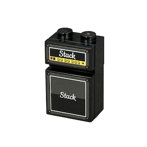 May include: A black toy amplifier stack with the word "Stack" printed on the front. The top of the amplifier has two black knobs. The front of the amplifier has a gold border and a series of small lights.