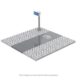 Op de afbeelding: Een model van een fietspad met een bord dat een fietspad aangeeft. De rijstrook is grijs met een wit fietssymbool en de tekst "CYCLE LANE". De omliggende bestrating is gemaakt van witte en grijze bakstenen.