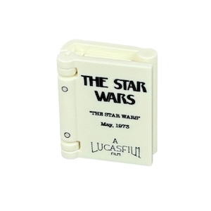 Könnte beinhalten: Ein cremefarbenes, klappbares, buchförmiges Sammlerstück mit dem Text "THE STAR WARS" und "May, 1973". Das Buch zeigt auch "A LUCASFILM film". Der Artikel ist ein Vintage-Sammlerstück von Star Wars.