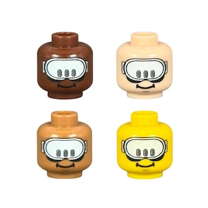 May include: Four Lego minifigure heads in various skin tones: brown, tan, light tan, and yellow. Each head features a black and white diving mask design and a smiling mouth.