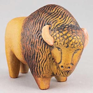 Może przedstawiać: Ceramiczna figurka bizona z brązowym korpusem i szczegółową głową. Głowa ma ciemnobrązową grzywę i wzorzysty wzór z brązowymi uszami. Figurka ma stylizowany, artystyczny design.
