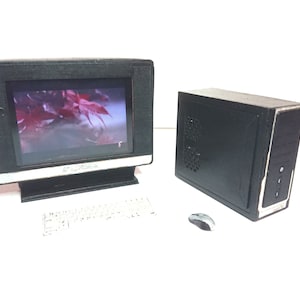 May include: A black desktop computer with a monitor, keyboard, and mouse. The monitor is displaying a video of a red maple leaf.