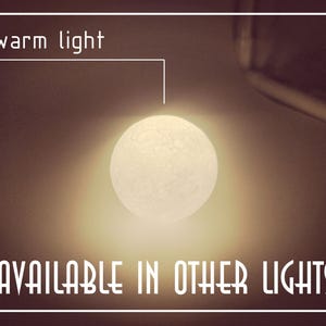 Op de afbeelding: Een gloeiende, bolvormige lichtbron die warm licht uitstraalt. De afbeelding bevat de tekst "warm light" en "AVAILABLE IN OTHER LIGHTS", wat wijst op verschillende verlichtingsopties.