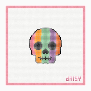 May include: A cross-stitch pattern featuring a skull with vertical stripes in pink, orange, light green, and purple, outlined in black. The skull has black eye sockets and a stitched mouth. The word daisy is stitched in pink in the bottom right corner.