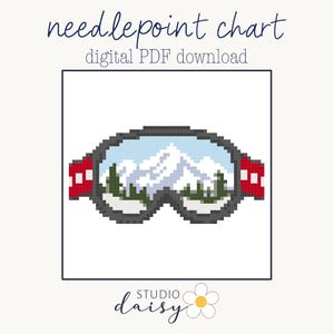 May include: A needlepoint chart digital PDF download featuring a pixel art design of ski goggles with a reflection of snow-capped mountains and pine trees. The goggles have a dark gray frame and red side straps. The text reads needlepoint chart digital PDF download and Studio Daisy.