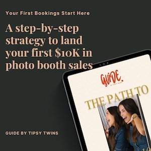 May include: A digital tablet displays the cover of a guide titled "The Path To" with two women. The guide is by Tipsy Twins and promises a step-by-step strategy to land your first $10K in photo booth sales. The background is dark.