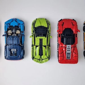 May include: Five toy cars in different colors: orange, blue, green, red, and yellow. The cars are all facing forward and have a similar design.