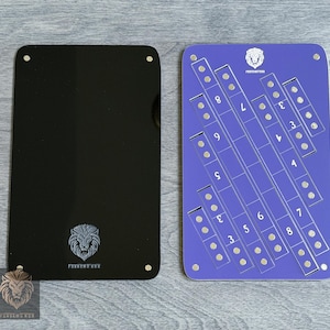 May include: A black rectangular game board with rounded corners and a purple game board with numbers and slots. The black board has a lion logo and the text "FORGEHUWOR". The purple board has numbers 3-9 and the same lion logo.