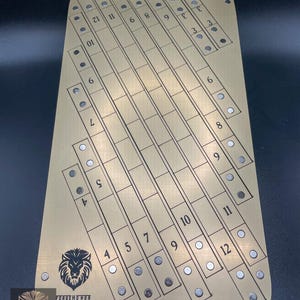May include: A gold metal board with a grid pattern and numbered columns. The board has a lion logo and the text "FORGE HONOR".