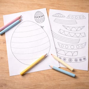 May include: Two sheets of white paper with Easter egg designs and coloring pencils. One sheet features a large egg outline with dotted lines for cutting and a decorated egg. The other sheet has decorative elements. Pencils are pink, blue, yellow, and orange.
