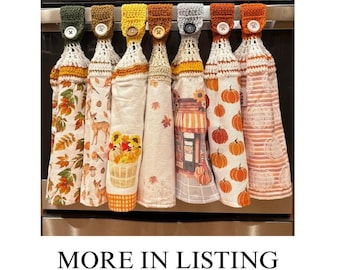 May include: Seven hanging kitchen towels with crocheted tops in various colors, each secured with a button. The towels feature autumn-themed patterns including pumpkins, sunflowers, deer, and fall foliage. The text MORE IN LISTING appears below.