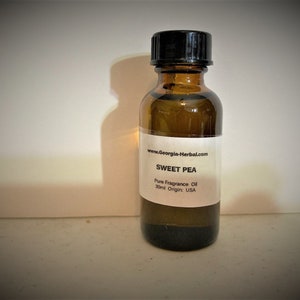 May include: A small brown glass bottle with a black lid, containing a clear liquid. The label reads "www.Georgia-Herbal.com SWEET PEA Pure Fragrance Oil 30ml Origin: USA".