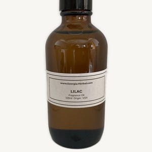May include: A brown glass bottle of Lilac fragrance oil. The label includes the text "Lilac Fragrance Oil 120ml Origin: USA" and the website address www.Georgia-Herbal.com. The bottle has a black cap.