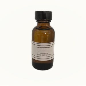 May include: A brown glass bottle with a black cap, filled with a golden liquid. A white label wraps around the bottle, displaying text including "Fragrance Oil" and "30ml (1 Oz) Origin: USA". The bottle is centered on a white background.
