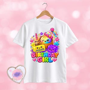 May include: A white t-shirt featuring a colourful graphic of a boba tea, a cupcake in a party hat, a stick of salted butter, and a purple cube, all with smiling faces. The text "BIRTHDAY GIRL" appears in large, multi-coloured, bubble-style letters.