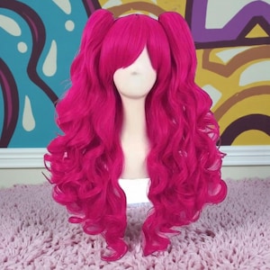 May include: A bright fuchsia wig with long, wavy hair and two high pigtails. The wig has a side-swept fringe and is styled on a mannequin head. The hair has a voluminous, curly texture, suitable for cosplay or costume events.