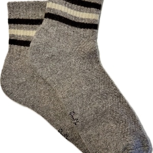 May include: A pair of gray ankle socks with black and white stripes. The socks are made of a soft, comfortable material.