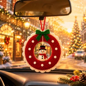 May include: A crocheted Christmas wreath ornament hanging from a rearview mirror. The circular wreath is red with white polka dots and a scalloped white border, topped with a green bow. A small crocheted snowman with a black hat hangs in the center.