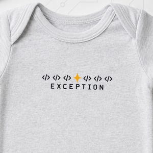 Könnte beinhalten: Ein hellgrauer kurzärmeliger Babybody mit einem Grafikdruck auf der Brust. Das Design zeigt eine Reihe von Code-Klammern mit einem orangefarbenen Sternsymbol in der Mitte, gefolgt von dem Wort EXCEPTION in schwarzen Großbuchstaben.