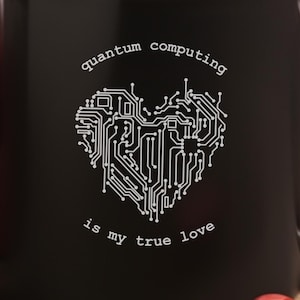 May include: Black coffee mug with a white design of a circuit board shaped like a heart. The text "quantum computing is my true love" is printed on the mug.