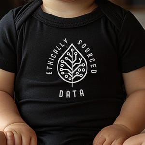 May include: Black baby bodysuit with short sleeves. The white graphic on the front features a leaf design with circuit board elements and the words "ETHICALLY SOURCED DATA". The baby is sitting on a patterned blanket.