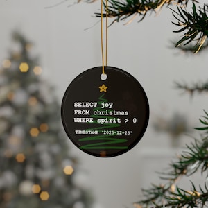 a Christmas ornament hanging from a tree branch. The ornament has a black background with white text and a green tree design.